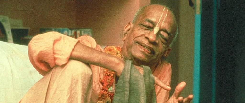 Śrīla Prabhupāda smiling and leaning back